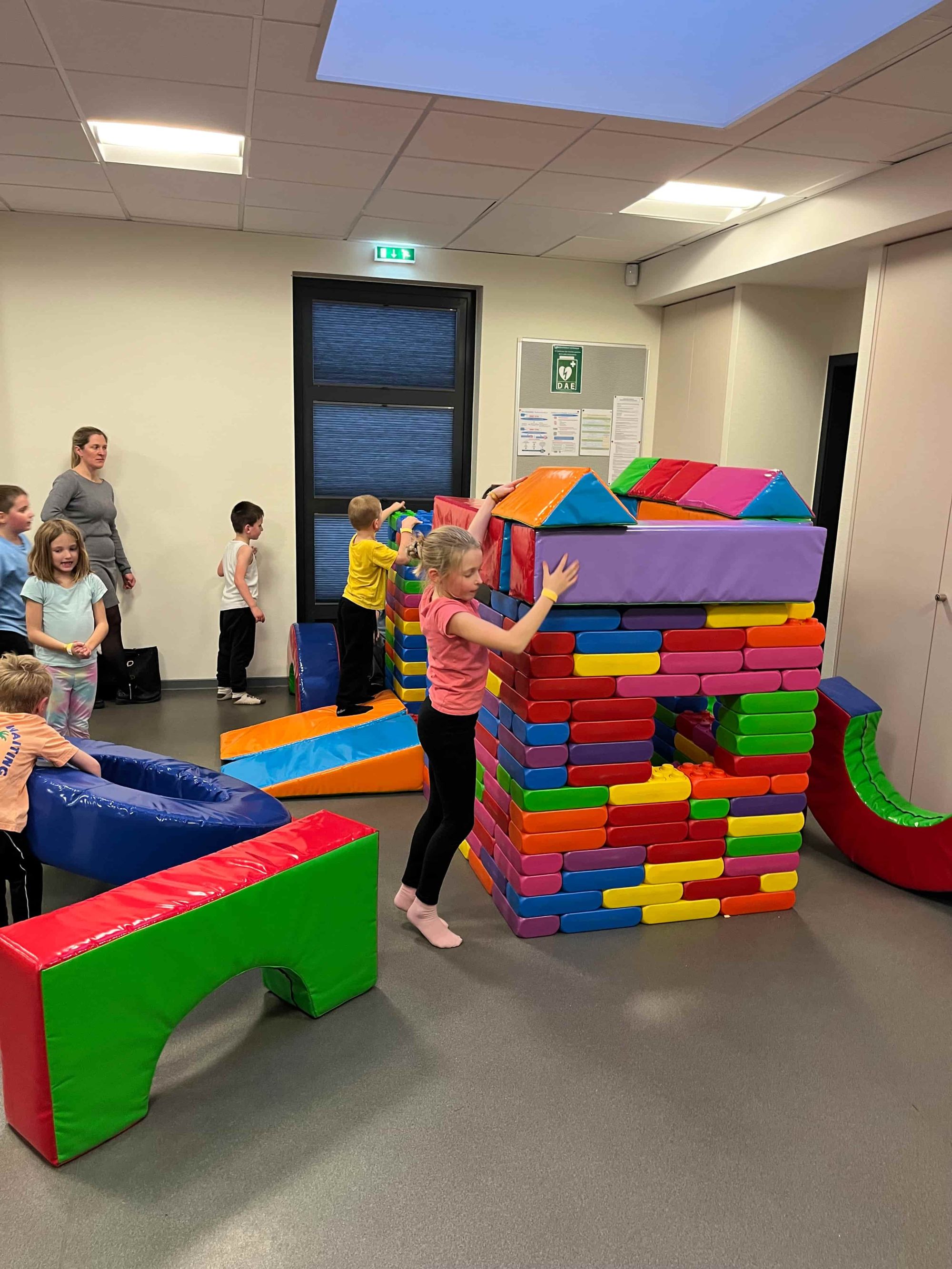 Enfants qui construisent une maison avec de grandes briques colorées en mousse en 2025