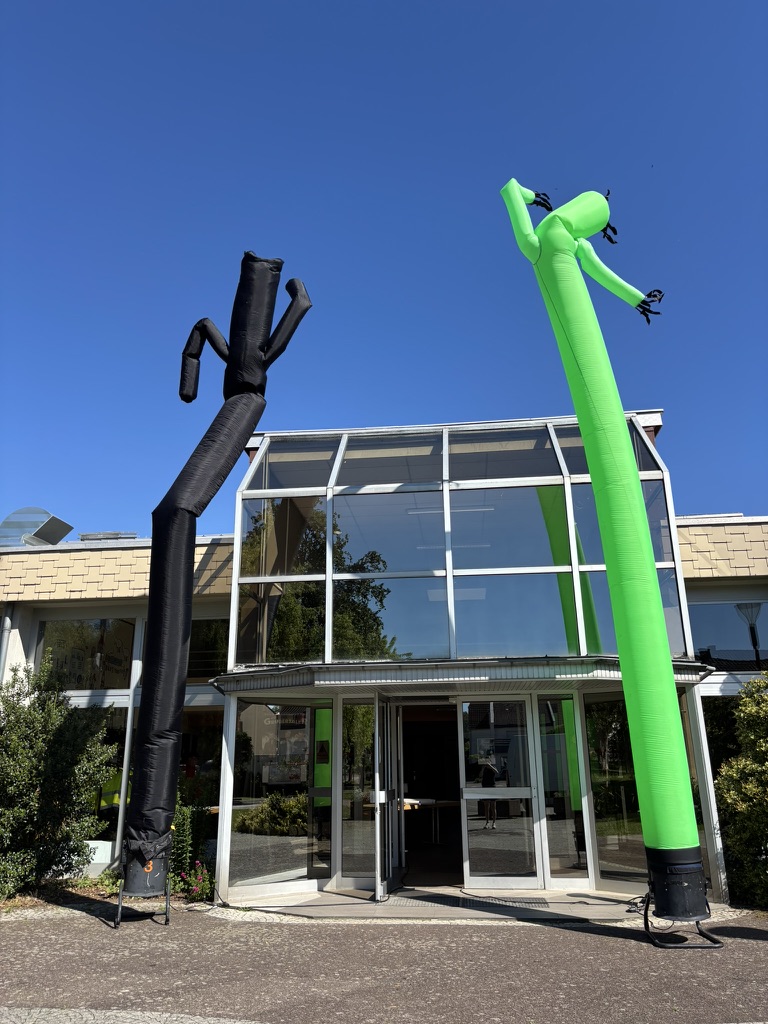 Deux Sky Dancers, un noir et un vert, devant l&rsquo;entr&eacute;e vitr&eacute;e de la salle